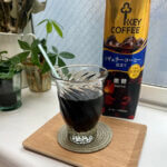 窓辺で涼し気なグラスに注がれたキーコーヒーリキッドコーヒーとそのパック